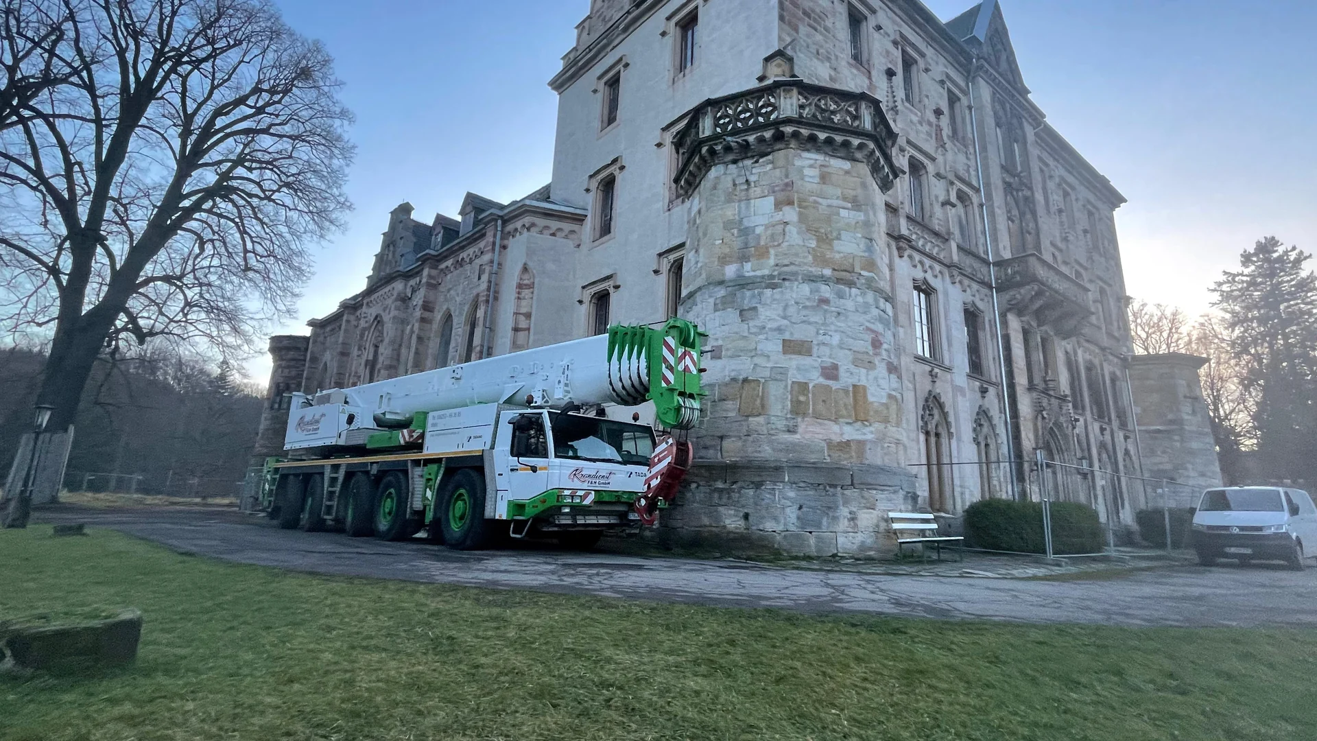 Weiß-grüner Autokran von Krandienst F&H vor einem Schlossgebäude aus Sandstein